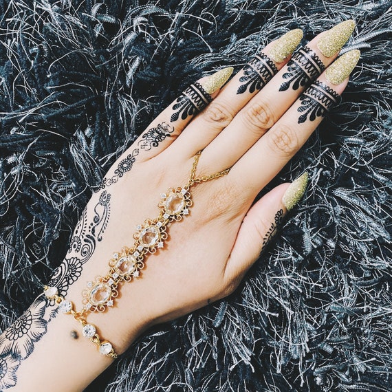 Hand of a girl with striking ring and bracelet, as well as a henna tattoo  lying on an opened bookrl Stock Photo - Alamy