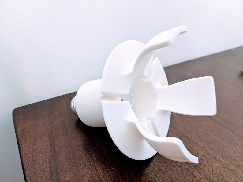 May include: White plastic light bulb holder with four prongs. The holder is designed to fit a standard light bulb.