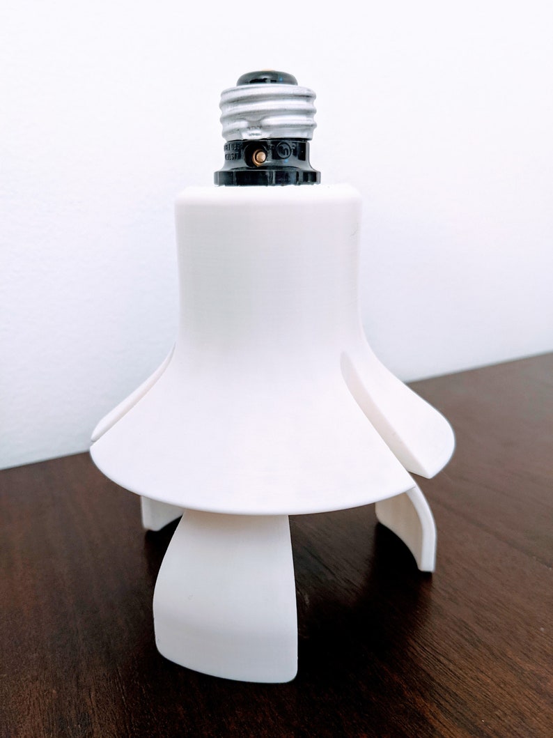 May include: White plastic light bulb adapter with a standard light bulb socket and three prongs for stability.