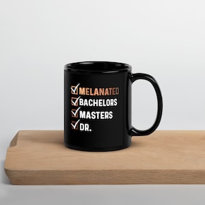 May include: Black ceramic coffee mug with a white checklist design. The checklist includes the words "Melanated", "Bachelors", "Masters", and "Dr."