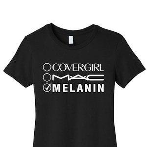Pode incluir: Camiseta preta com texto branco que diz "Covergirl, MAC, Melanin" com uma marca de verificação ao lado de "Melanin".