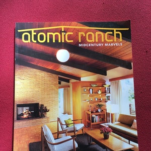 May include: A magazine cover for Atomic Ranch, a publication about mid-century modern homes. The cover features a photo of a living room with a fireplace, wood paneling, and a large window. The text on the cover reads "Atomic Ranch" and "Midcentury Marvels". The issue is from Winter 2008 and features articles about Atlanta's Northcrest, PNW Kirk Design, custom Portland MCM, and blue collar digs.