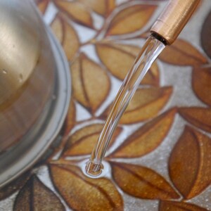 May include: A close-up of a copper tap with water flowing into a sink with a leaf pattern.