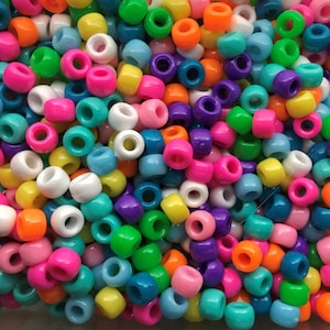 May include: A large pile of colorful plastic beads in various shades of blue, green, pink, yellow, orange, and purple. The beads are all the same size and shape, and they are arranged in a random pattern.