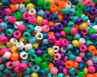 Puede incluir: Un montón grande de cuentas de plástico de colores en varios tonos de azul, verde, rosa, amarillo, naranja y morado. Las cuentas son todas del mismo tamaño y forma, y están dispuestas en un patrón aleatorio.