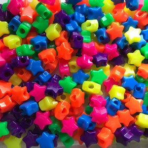 May include: A large pile of colorful star-shaped plastic beads. The beads are in a variety of bright colors, including red, orange, yellow, green, blue, and purple.