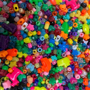 May include: A large assortment of colorful plastic beads in various shapes, including stars, hearts, and animals. The beads are perfect for crafting and jewelry making.