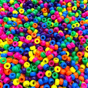 May include: A large pile of colorful plastic beads. The beads are round and have a hole in the center. The beads are in a variety of colors, including red, orange, yellow, green, blue, purple, and pink.