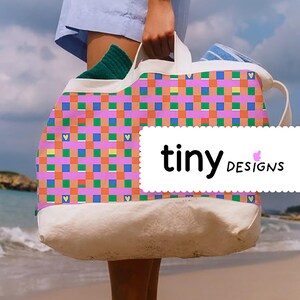 Peut inclure: Un sac fourre-tout en toile blanche avec un motif à carreaux rose, orange, bleu et vert et de petits cœurs jaunes. Le sac a une bordure blanche et le texte "tiny DESIGNS" est imprimé sur le devant.
