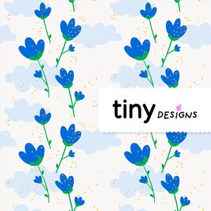 Peut inclure: Motif répété de fleurs bleues avec des tiges et des feuilles vertes, sur fond crème avec des nuages bleu clair et des mouchetures dorées. Le texte "tiny designs" est affiché dans un rectangle blanc.