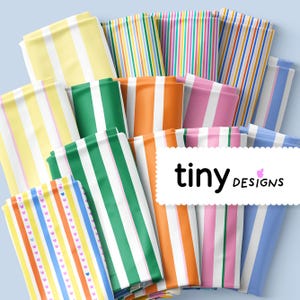 Peut inclure: Plusieurs paquets de tissus rayés colorés, dans des tons de jaune, vert, orange, rose et bleu. Le tissu présente des rayures verticales de différentes largeurs et motifs. Le texte "tiny designs" est affiché sur une étiquette blanche.