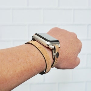 May include: A close-up of a person's wrist wearing a tan leather watch band with a silver Apple Watch.