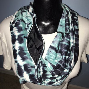 May include: A teal and black tie-dye infinity scarf with a zippered pocket.
