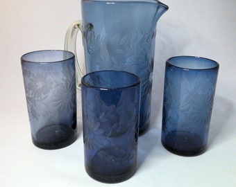 May include: A set of four blue glass pitcher and tumblers with an etched floral design.