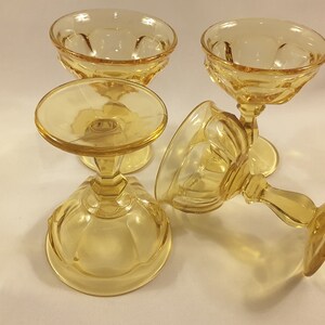 May include: Four amber-colored glass dessert cups with a fluted design. The cups are on a white surface.