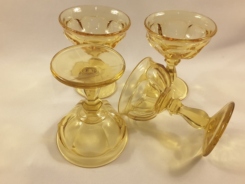 May include: Four amber-colored glass dessert cups with a fluted design. The cups are on a white surface.