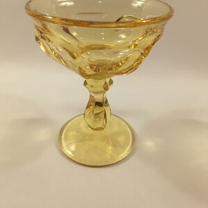 May include: A yellow glass dessert dish with a fluted bowl and a pedestal base.
