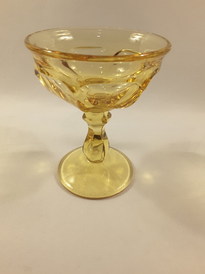 May include: A yellow glass dessert dish with a fluted bowl and a pedestal base.