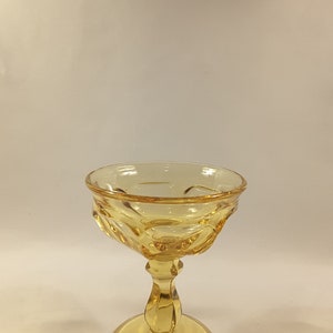 May include: A yellow glass goblet with a fluted bowl and a short stem. The goblet has a wide base.