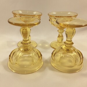 May include: Set of four amber glass footed dessert dishes. The dishes have a fluted design and a round base.