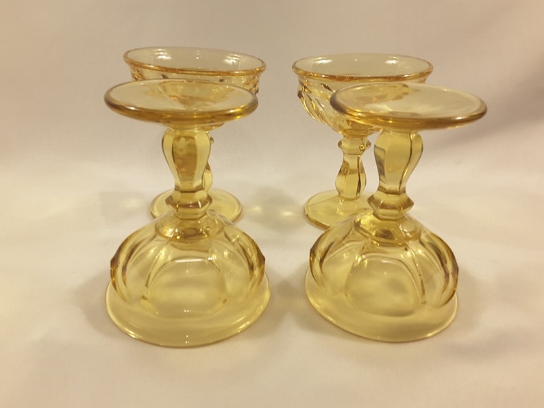 May include: Set of four amber glass footed dessert dishes. The dishes have a fluted design and a round base.