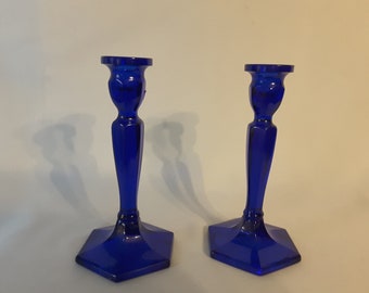 May include: Two cobalt blue glass candle holders with a hexagonal base and a fluted design.