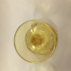 May include: A clear yellow glass goblet with a fluted design. The goblet is empty and has a round base.