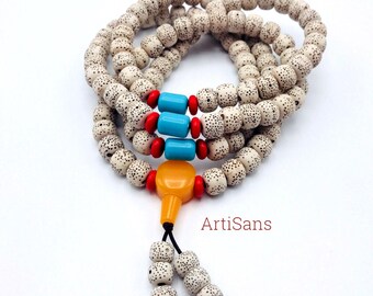 May include: A white prayer bead mala necklace with red, blue, and yellow accents. The beads are made of Rudraksha seeds and are strung on a black cord. The mala is approximately 108 beads long and is perfect for meditation or prayer.