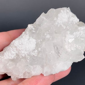 May include: A cluster of white calcite crystals with a rough, textured surface. The crystals are translucent and have a slightly milky appearance.