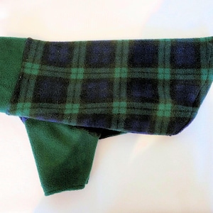 May include: A green and blue plaid fleece dog sweater with a fold-over collar.