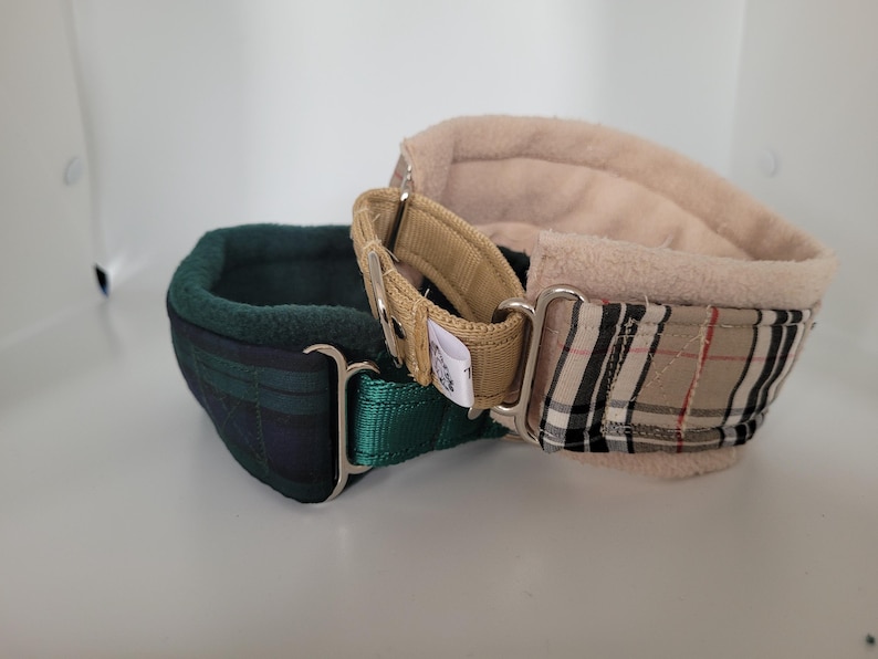 Puede incluir: Dos collares para perros. Uno es de cuadros verdes y azul marino con una correa verde y herrajes plateados. El otro es beige con un estampado de cuadros en negro, beige y rojo, con una correa beige y herrajes plateados. Ambos collares tienen un interior suave y acolchado.