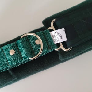 Puede incluir: Un collar para mascota forrado en vell&oacute;n verde oscuro con una correa de nailon verde esmeralda, herrajes de metal plateado y una peque&ntilde;a etiqueta de tela blanca con un dibujo lineal negro de una ardilla sosteniendo una bellota.