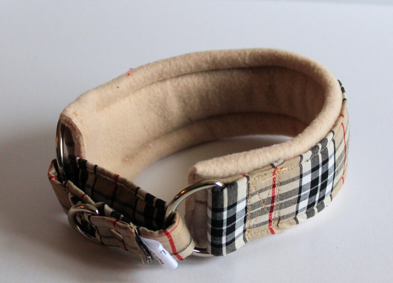 Puede incluir: Un collar acolchado para perros con forro polar beige y un estampado a cuadros en beige, negro y rojo. El collar tiene una anilla en D de metal y una hebilla. Dise&ntilde;o cl&aacute;sico y elegante.