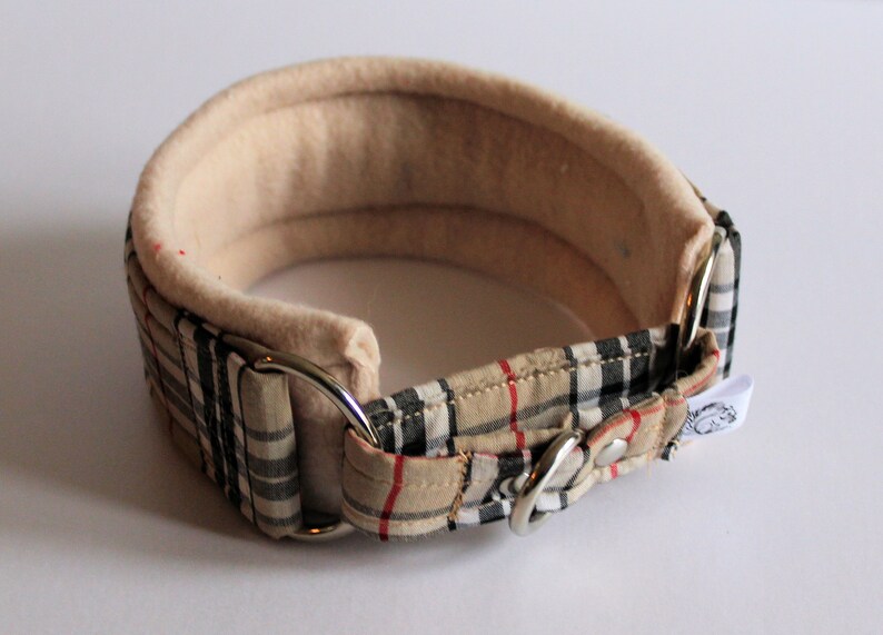 Puede incluir: Un collar acolchado para perros, beige y a cuadros. El collar tiene un interior suave de color crema y un exterior a cuadros con cuadros beige, negros y rojos. Cuenta con herrajes met&aacute;licos plateados.