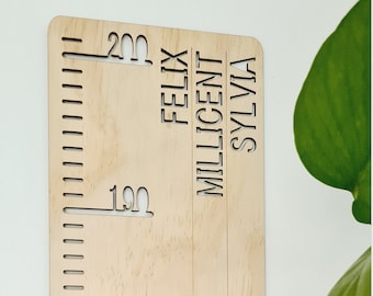 May include: A wooden growth chart with a ruler marked in centimetres from 160 to 200. The names Felix, Millicent, and Sylvia are cut out on the chart.