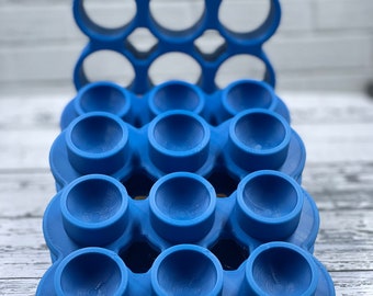 May include: A blue silicone fidget toy with a grid of 18 round dimples. The toy is designed to be pressed and popped, providing a satisfying sensory experience.