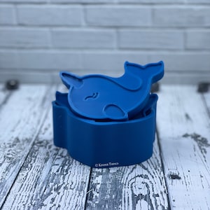 May include: A blue plastic dolphin-shaped container with the text "Kinder Things" on the bottom.