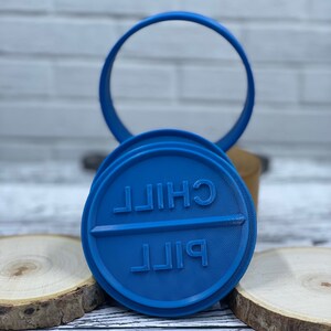 May include: Blue plastic cookie cutter shaped like a pill with the words "CHILL PILL" embossed on it.