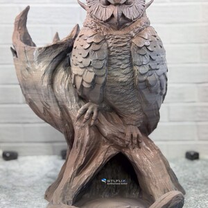 May include: A detailed brown owl sculpture perched on a tree branch. The owl has textured feathers and a stern expression. The sculpture is a decorative item, possibly for home decor.