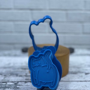 May include: Blue plastic cookie cutters shaped like a cat and a paw print.