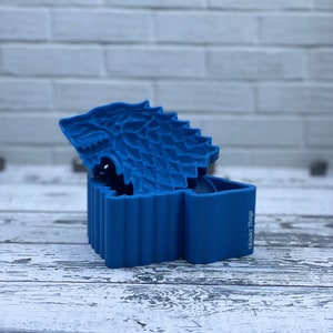 May include: A blue plastic box shaped like a direwolf head, with the words "Kinder Things" on the side.