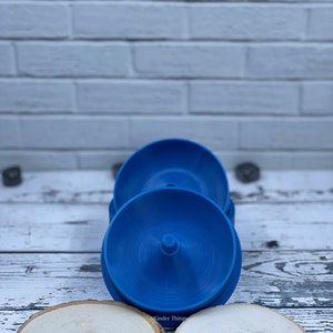 May include: Three blue plastic stacking rings with a small knob on the top of each ring. The rings are stacked on top of each other on a white wooden surface. The rings are for stacking and sorting toys.