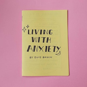 May include: A yellow booklet with the title "LIVING WITH ANXIETY" in black handwritten text. The author's name, "BY EVIE BASCH", is also written in black handwritten text.
