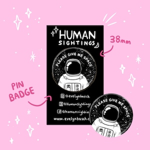 May include: A black and white pin badge featuring an astronaut in a spacesuit with the text "PLEASE GIVE ME SPACE" around the astronaut. The text "HUMAN SIGHTINGS" is at the top of the badge. The badge is 38mm in diameter.