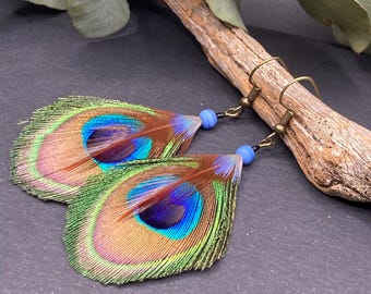 Pendientes de plumas naturales de pavo real y cuentas de vidrio azul.