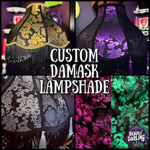 Pu&ograve; includere: Un collage di paralumi damascati personalizzati in vari colori. I paralumi presentano motivi ornati e finiture con frange. I colori includono oro, viola, nero, argento, rosa e verde. Il testo "CUSTOM DAMASK LAMPSHADE" &egrave; visualizzato al centro.