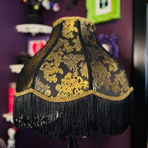 Pu&ograve; includere: Paralume nero con motivo floreale dorato e frange nere. Il paralume ha un bordo dorato lungo i bordi superiore e inferiore. Questo paralume decorativo &egrave; per una lampada da tavolo o da terra, aggiungendo un tocco di eleganza.