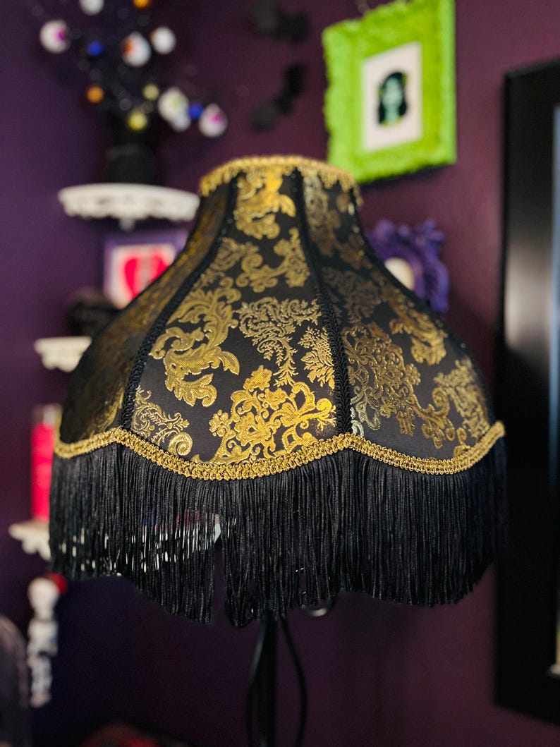 Pu&ograve; includere: Paralume nero con motivo floreale dorato e frange nere. Il paralume ha un bordo dorato lungo i bordi superiore e inferiore. Questo paralume decorativo &egrave; per una lampada da tavolo o da terra, aggiungendo un tocco di eleganza.