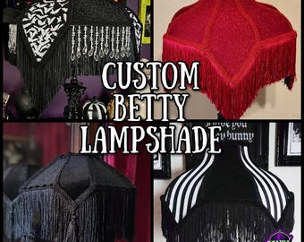 Può includere: Un collage di quattro paralumi Betty personalizzati. I paralumi sono neri, rossi e a righe bianche e nere, con frange ed elementi decorativi. Il testo "CUSTOM BETTY LAMPSHADE" è al centro dell'immagine.