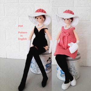 May include: Crocheted doll wearing a black dress, white gloves, and a wide-brimmed hat with a pink crown. The doll is seated on a decorative container. The text "PDF Pattern in English" is visible.